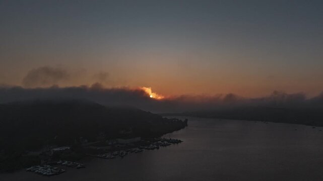 Sunset Timelapse as clouds pass by over a small harbor.  Shot with DJI Air 3S in 4k, non moving, fixed view.