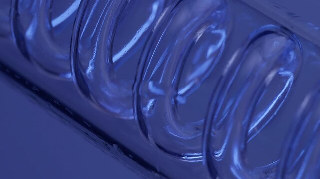 Slow motion macro close up of plastic spiral notebook binding coil on desk with blue reflective lighting. tracking shot lateral movement.