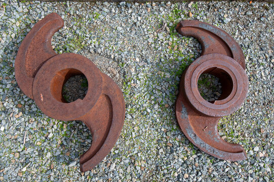 Rusted metal parts on gravel surface in daylight