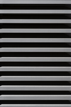 Lines create shadows on a gray surface in sunlight