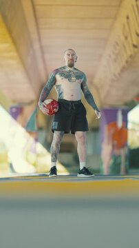 Tattooed football player holding a ball outdoors