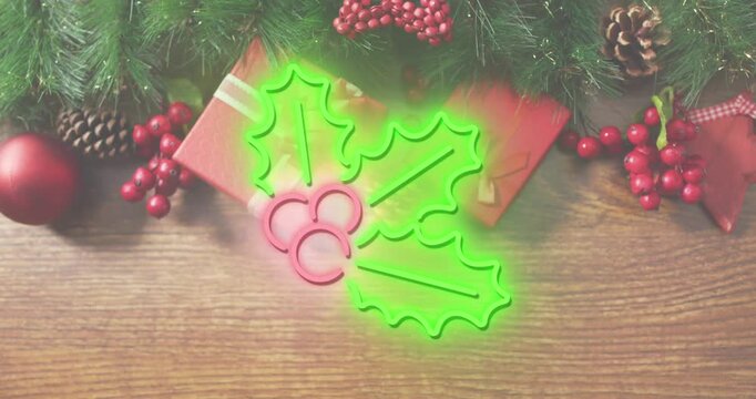 Animation of neon mistletoe icon over christmas gifts and decorations on wooden surface