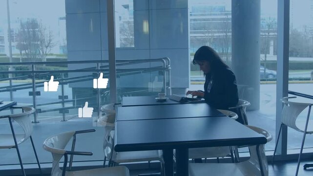 Animation of thumbs up icons over woman using digital tablet at office