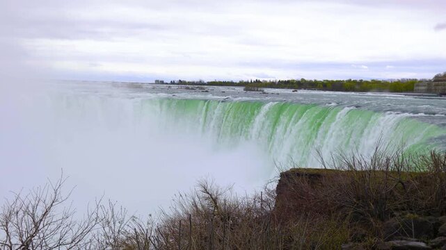 4K aerial view of Niagara Falls with powerful waterfalls, mist and river flow, showing iconic natural landscape on USA and Canada border.