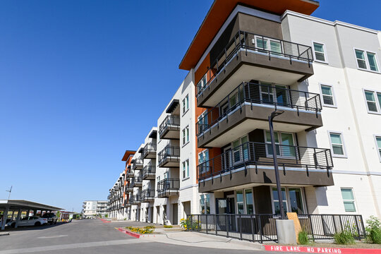 Exterior of newly completed multi building apartment complex with balconies and street access, representing residential housing development, urban living, and rental property infrastructure