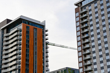 High rise residential towers with construction crane between buildings, representing urban housing development, vertical construction, and multifamily real estate growth © Eduardo Barraza