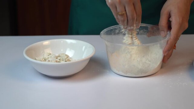 Close up Hand Coating Fresh Shrimp with Seasoned Flour in Plastic Bowl