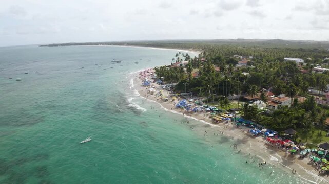 4K drone view of Porto de Galinhas beach, Brazil, with turquoise water, boats and coastal town, showing tropical landscape and tourism.