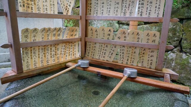 Kyoto, Japan - Oct 11 2025, 4k, close up view of the stand hung with small paper ema plaques with calligraphy, on a small Tsukubai pool, in Kiyomizu-dera Temple, without people, Kyoto, Japan