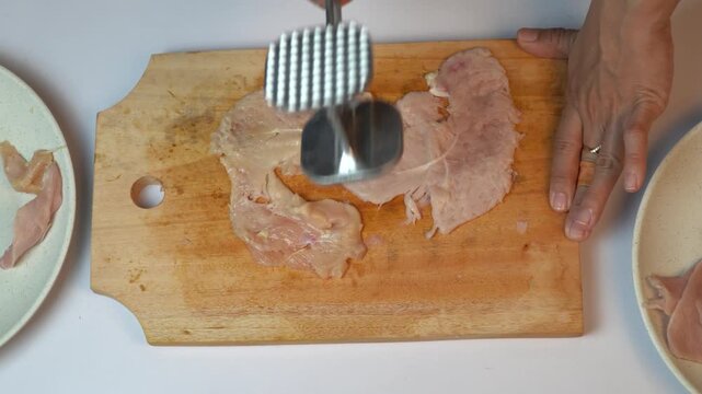 Close Up of Pounding Raw Chicken Fillet Using Meat Tenderizer Tool