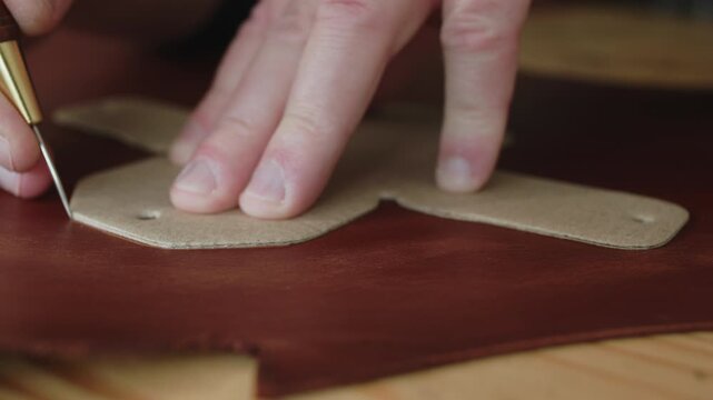 Craftsman tracing pattern on leather with awl