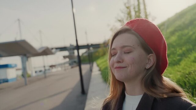 White woman checking watch by waterfront commuter glancing at wrist with playful annoyed expression, city platform and harbor in background, casual coat and beret, travel timing and everyday schedule