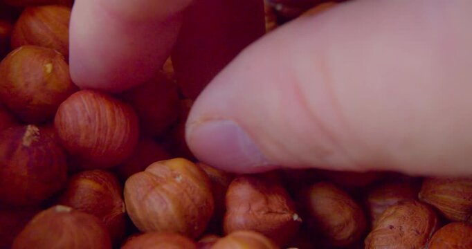 Close-up video of fingers taking shelled hazelnuts from a plate.