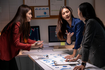 Fototapeta premium Businesswomen collaborating on data overworking late night
