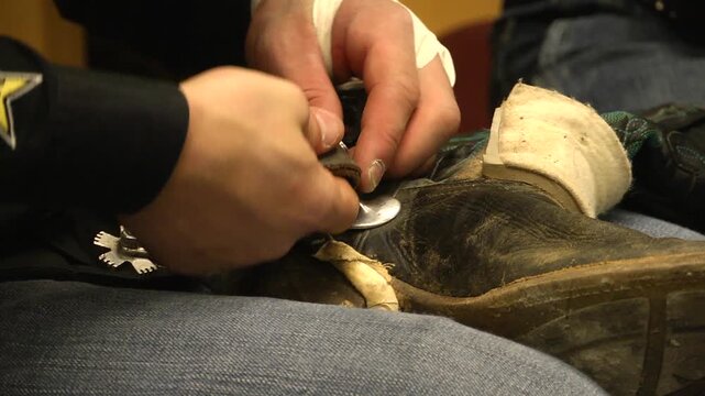 Close up of cowboy strapping up leather boots 