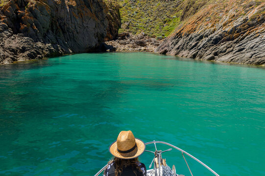 Girl with sun hat on the bow of a pleasure boat coasting into the green seas of Salmon Inlet, Althorpe Island, South Australia