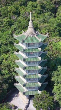 Vertical screen Close Aerial Of Pagoda Spire Surrounded By Emerald Forest Near Da Nang, Detailed Green Tiles, Carved Stone Base, Shadowed Stairwell And Quiet Pathway, Spiritual Solitude
