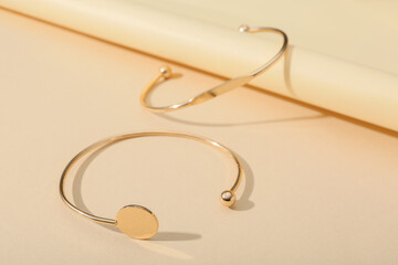 Beautiful golden bracelets on beige background, closeup
