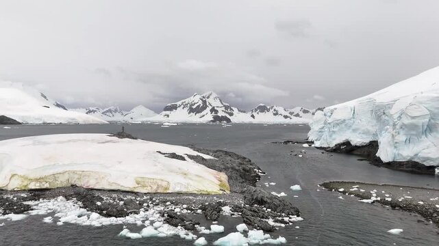 Cinematic aerial moving forward and raising over the ice shelves of Paradise Bay to reveal the massive snow-capped peaks of Rojas Peak and Bryde Peak on the Antarctic Peninsula