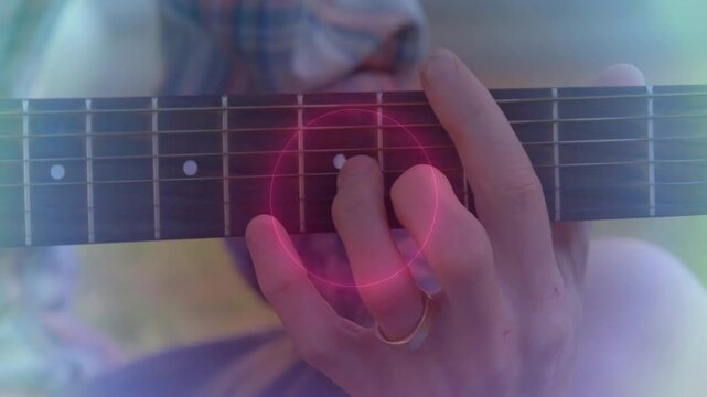 Male guitarist pressing frets and causing pulsing rings while shifting chords for music practice