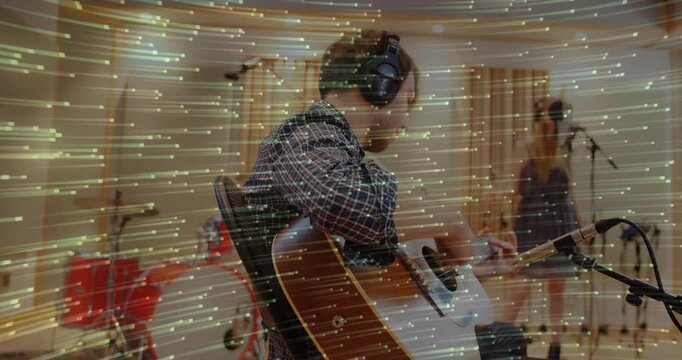 Guitarist tuning, strumming in studio for take, singer leaning to mic while streaks across frame