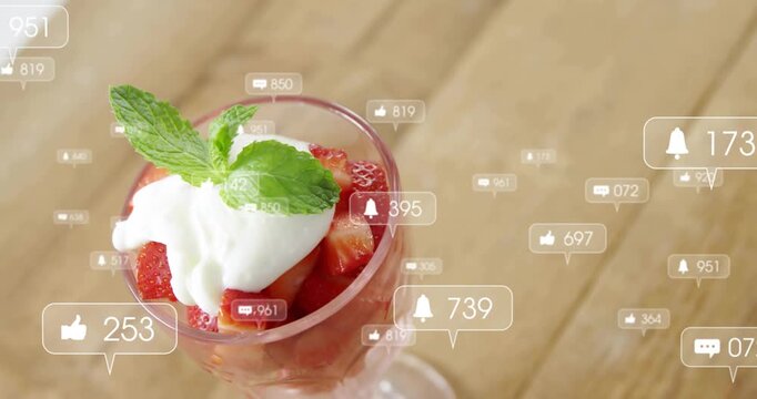 Badges appearing peaking and fading, glass with strawberries and cream tracking likes on wood table