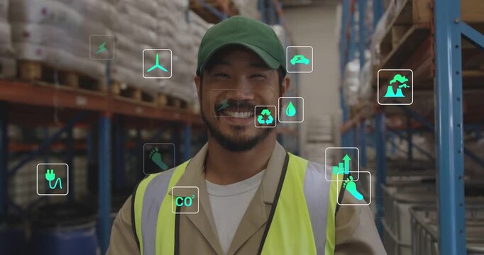Warehouse worker tapping tablet, looking up smiling as green icons grow and checking energy metrics