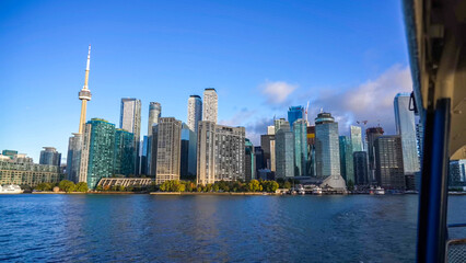 Fototapeta premium A vibrant view of the Toronto skyline from the water, featuring the CN Tower and modern waterfront skyscrapers under a clear blue sky
