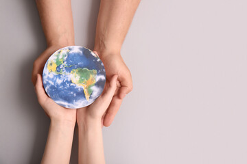 Female hands with paper planet Earth on grey background. World Oceans Day © Pixel-Shot