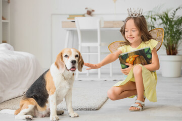 Obraz premium Cute little girl with Beagle dog and book in bedroom