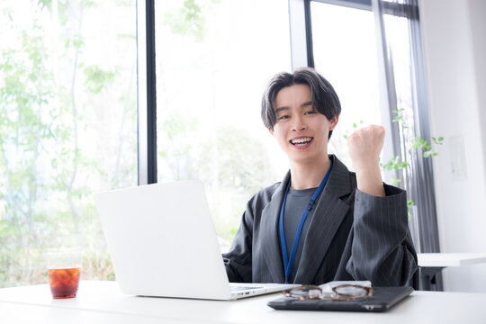 仕事で成果を出して喜ぶ若手社員の成功と達成のビジネスシーンのガッツポーズのカメラ目線　ポジティブ