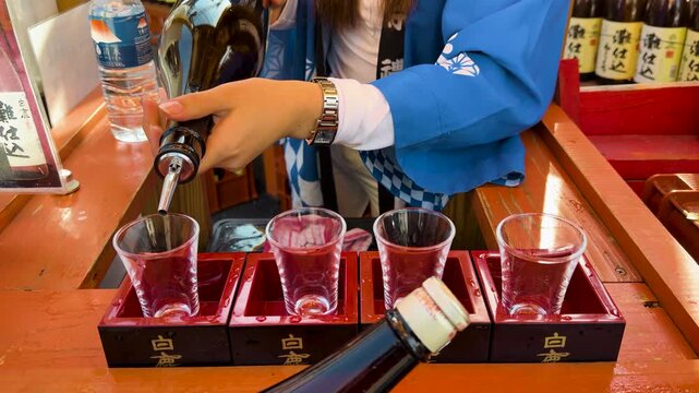 Japanese Woman Pouring Sake Into Glass Cups Inside Traditional Wooden Masu Boxes