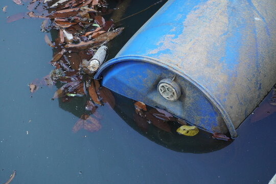A blue barrel floating in water with half of its body above the surface.