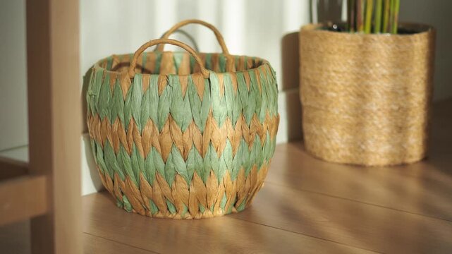 Woven basket for laundry and home decoration standing on wooden floor with warm sunlight.