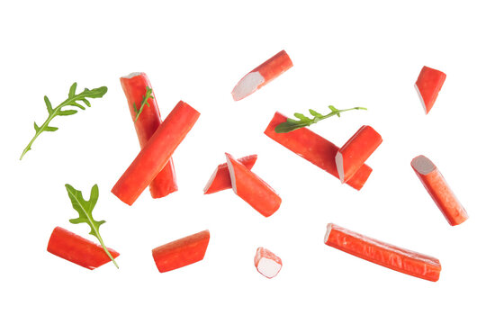 Tasty crab sticks and arugula leaves flying on white background
