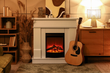 Obraz premium Interior of cozy living room with fireplace, guitar and commode in evening