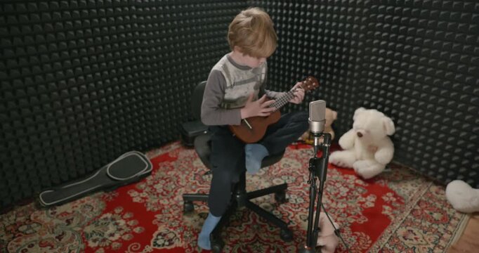 Boy Play Music on Ukulele Instrument in Home Studio. 4K 10-bit