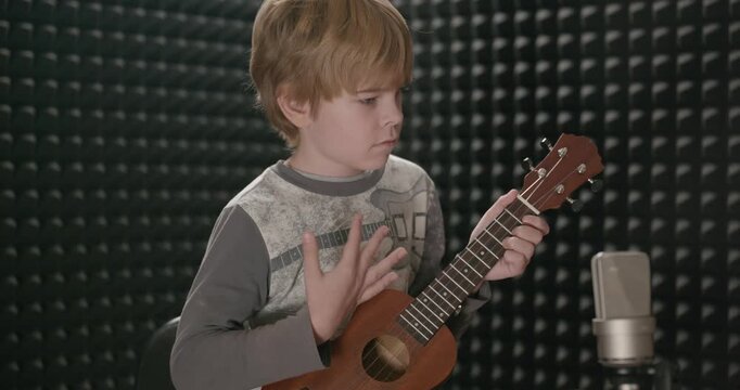 Boy Play Music on Ukulele Instrument in Home Studio. 4K 10-bit