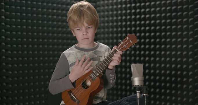 Boy Play Music on Ukulele Instrument in Home Studio. 4K 10-bit