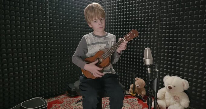 Boy Play Music on Ukulele Instrument in Home Studio. 4K 10-bit