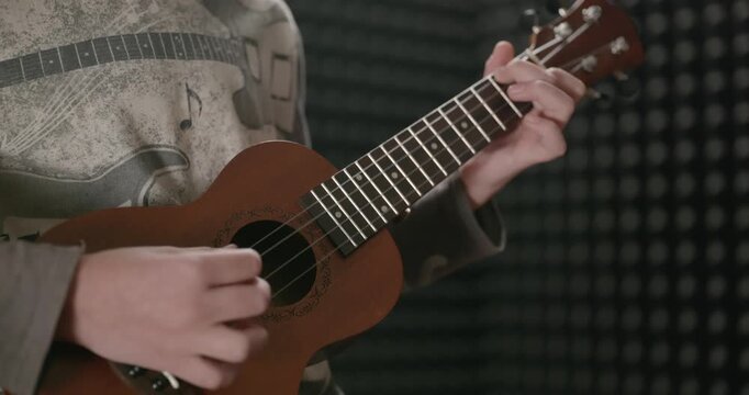 Boy Play Music on Ukulele Instrument in Home Studio. 4K 10-bit