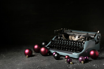 Obraz premium Vintage typewriter with Christmas balls on black background