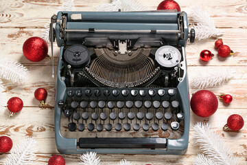 Obraz premium Vintage typewriter with red Christmas balls and fir branches on white wooden background