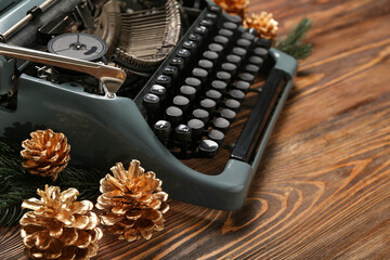 Obraz premium Vintage typewriter with pine cones and Christmas tree branches on wooden background, closeup