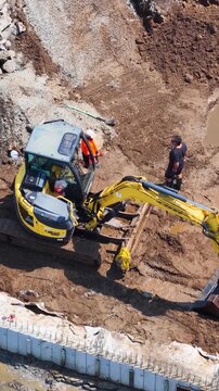 Vertical Aerial View of Mini Excavator and Workers at Construction Site