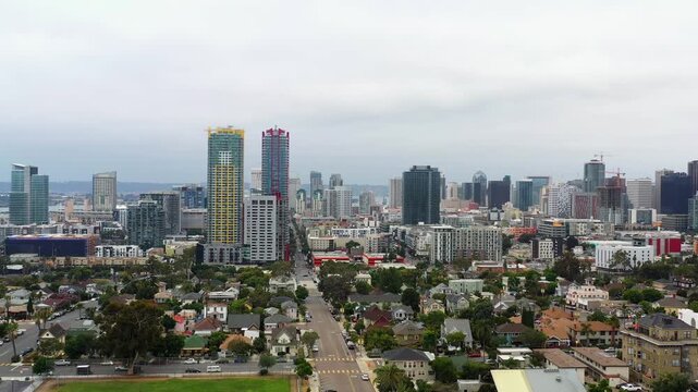 Drone flying toward the San Diego skyline with city buildings illuminated by early morning light.
