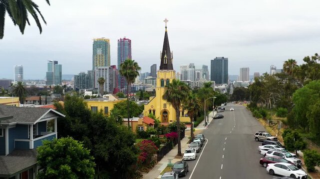 Drone rising above a church revealing the downtown San Diego skyline in early morning light.