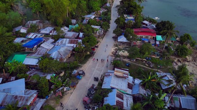 Children playing in street of developing slum village. Smooth aerial view drone