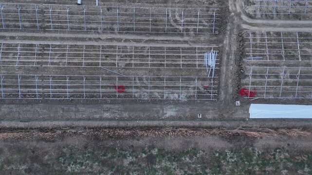 Construction site in a rural field with rows of metal frames being installed for a future solar farm, marking progress toward renewable energy and reduced carbon footprint