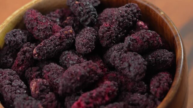 Dried black mulberries on a bowl closeup.